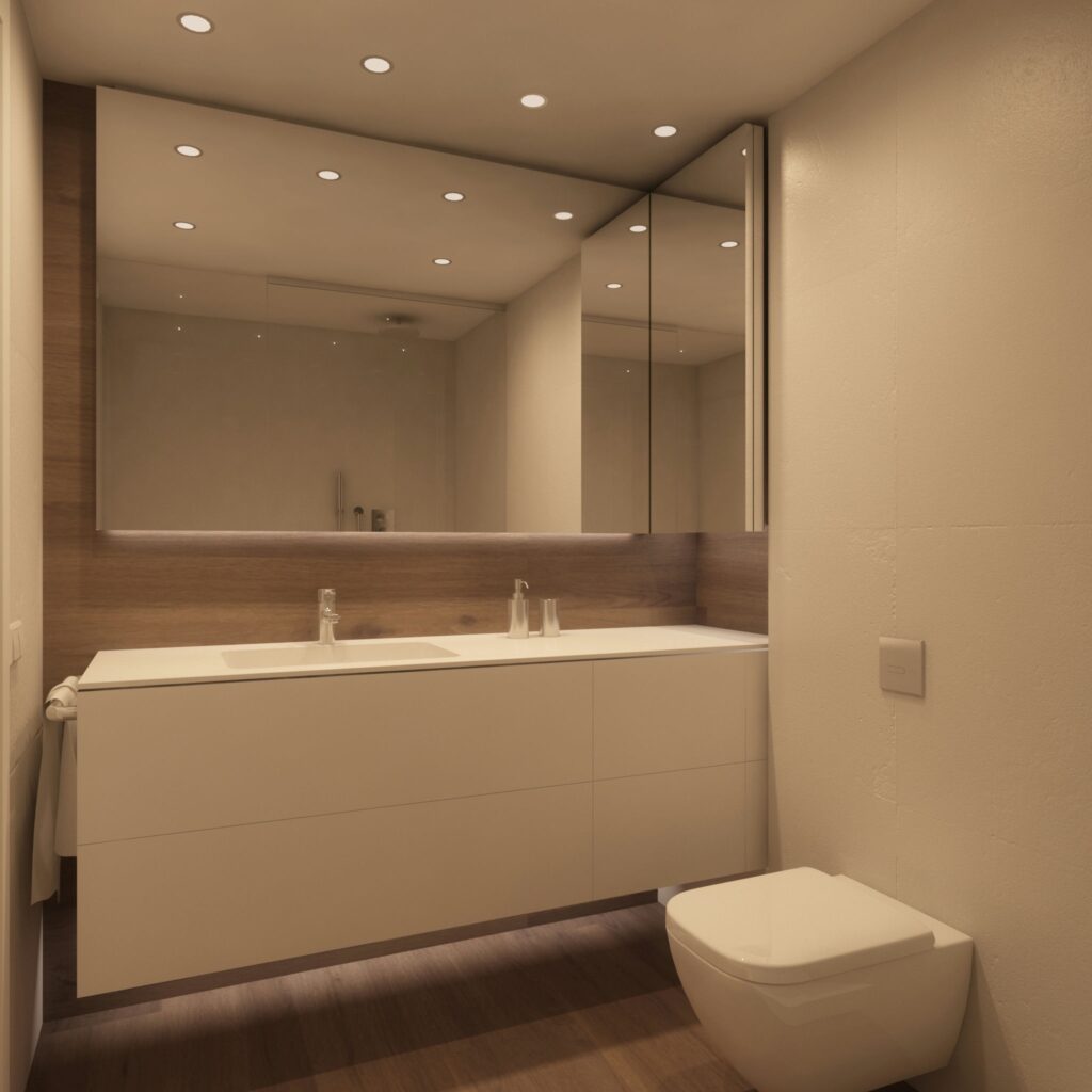 Diseño de interiores de baño de alta gama en Barcelona Baño moderno y funcional en Barcelona con mobiliario de madera clara, lavabo minimalista y gran espejo sin marco, iluminado con luz natural y detalles sofisticados