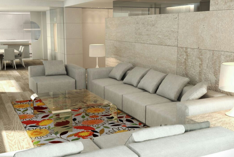 Salón contemporáneo en Barcelona con sofá gris claro, mesa de cristal y alfombra floral, destacando iluminación natural y detalles arquitectónicos de alta calidad.