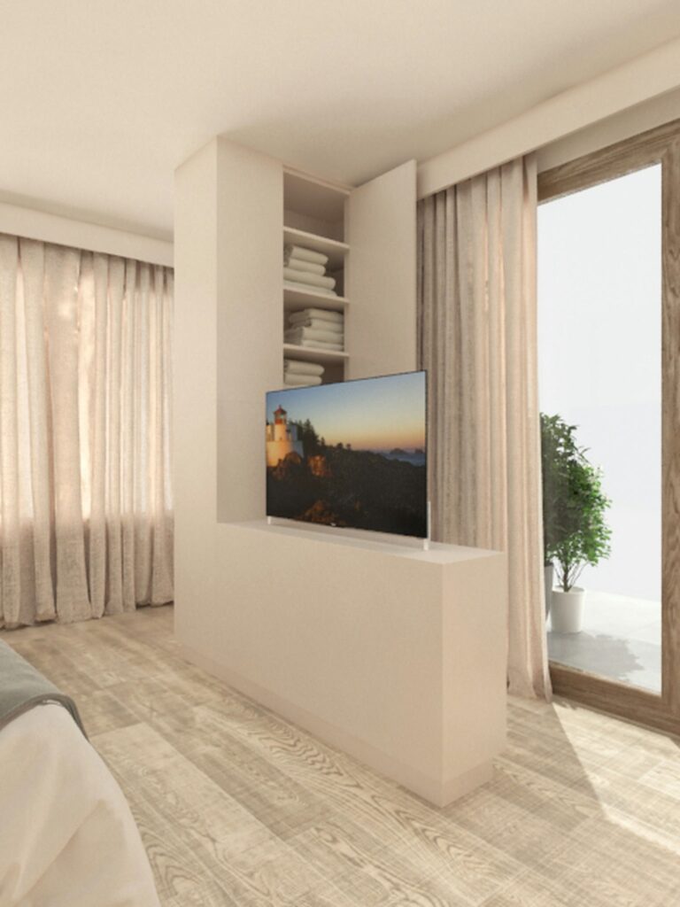Diseño de Interiores Moderno en un Apartamento de Alta Gama en Barcelona Apartamento de diseño moderno en Barcelona que presenta un espacio de vida minimalista, con un televisor montado sobre un mueble de almacenamiento blanco, estantes abiertos con toallas apiladas, y una gran ventana que permite la entrada de luz natural a través de cortinas transparentes.