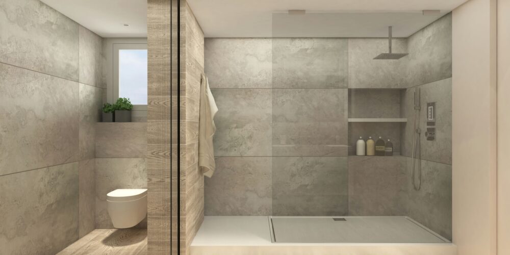 Interior de baño contemporáneo en Barcelona con materiales de alta calidad, paredes grises texturizadas, mampara de vidrio, inodoro minimalista y suelo de madera. Iluminación natural ilumina el espacio, destacando la funcionalidad y estética del diseño.