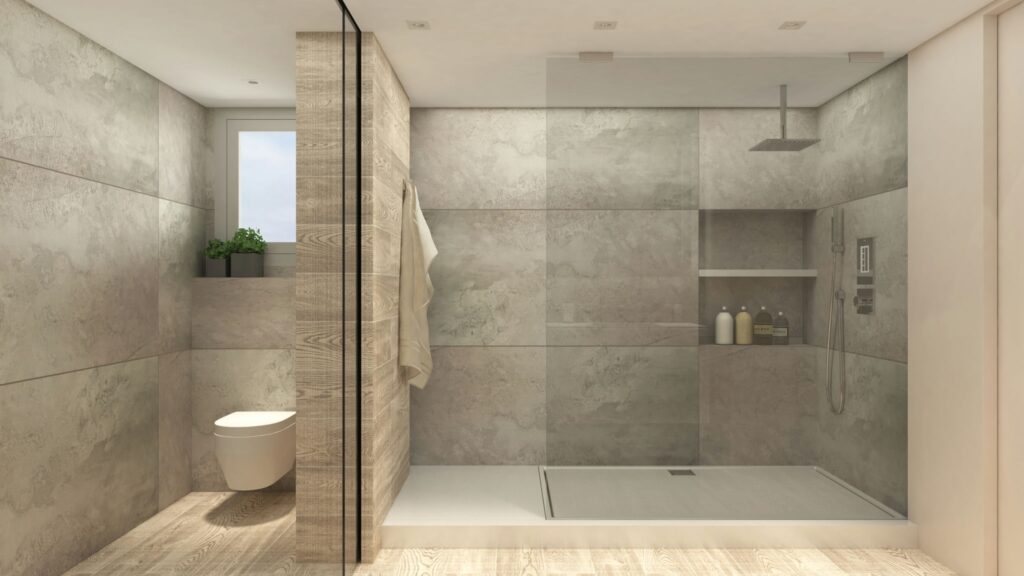 Diseño de interiores moderno en baño de alta gama en Barcelona Interior de baño contemporáneo en Barcelona con materiales de alta calidad, paredes grises texturizadas, mampara de vidrio, inodoro minimalista y suelo de madera. Iluminación natural ilumina el espacio, destacando la funcionalidad y estética del diseño.