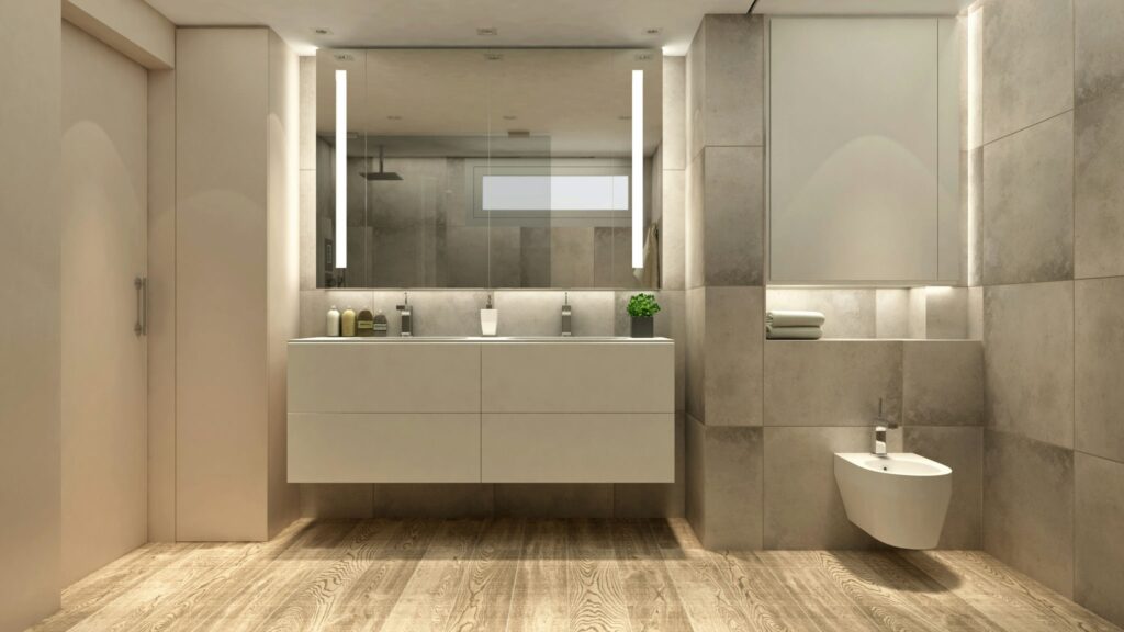Baño de diseño moderno y de alta gama en Barcelona con acabados elegantes Cuartos de baño: Baño contemporáneo en Barcelona con mueble minimalista, espejo grande y grifería moderna, acentuado por azulejos gris claro y piso de madera natural, iluminado por luz natural.