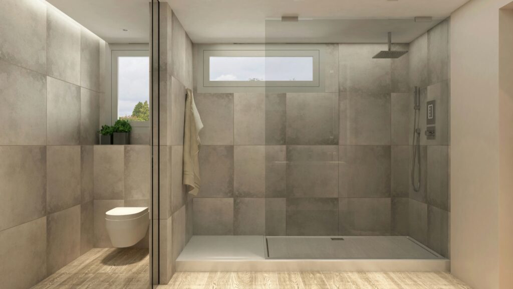 Diseño Moderno de Baño en Barcelona con Materiales de Alta Calidad Baño moderno y espacioso en Barcelona con ducha de vidrio, azulejos grises, iluminación natural, y suelos de madera, destacando elementos de diseño contemporáneo y funcionalidad.