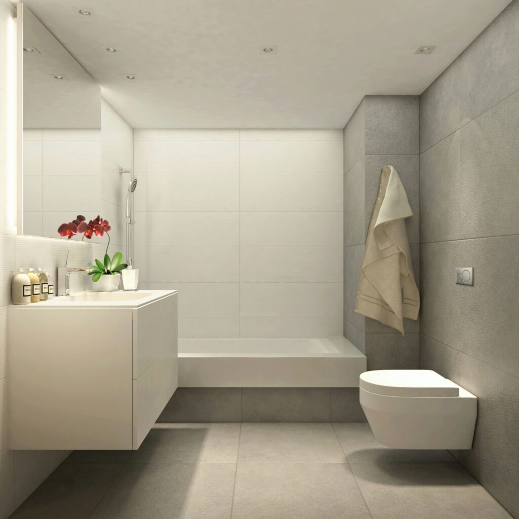 Diseño de baño moderno de alta gama en Barcelona | Arquitectura contemporánea Baño moderno con diseño de alta gama en Barcelona, destacando su estética minimalista, paredes y suelos texturizados, vanidad blanca estilizada, ducha con cabezal de lluvia y elementos decorativos naturales.