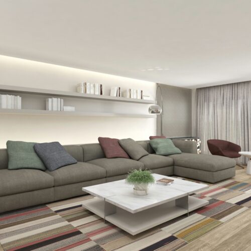 Salón contemporáneo en Barcelona con sofá gris oscuro, cojines coloridos, mesa de café blanca, alfombra de rayas vibrantes y estanterías flotantes. Iluminación natural y detalles arquitectónicos sofisticados.