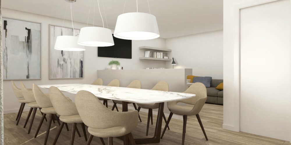 Comedor moderno en un proyecto de diseño interior de alta gama en Barcelona, con mesa de mármol y sillas tapizadas en beige. Iluminado por focos colgantes elegantes y arte contemporáneo en las paredes, con una acogedora sala de estar al fondo.