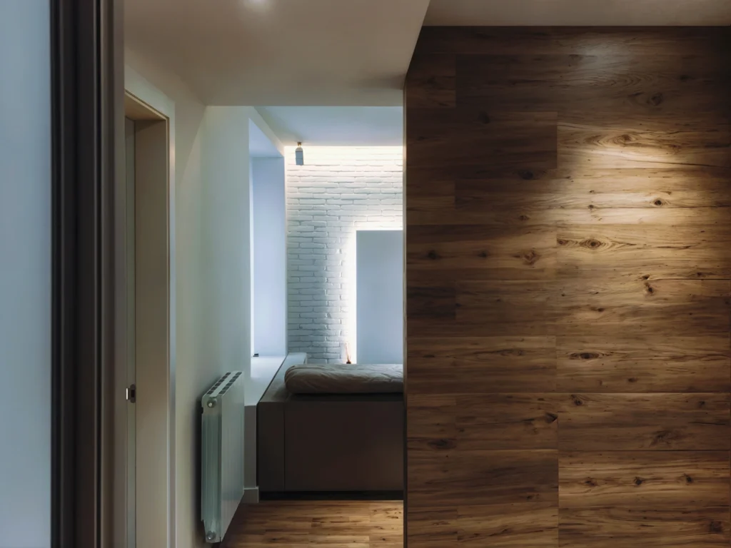 Diseño de Interiores Modernos en Barcelona: Pasillo Iluminado con Madera y Ladrillo Pasillo luminoso en un diseño de interiores moderno en Barcelona, con paredes de madera y ladrillos blancos, destacando la funcionalidad y estética del espacio.