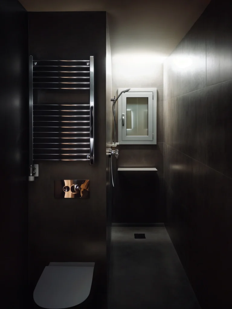 Baño Moderno y Elegante en Barcelona: Diseño de Interiores de Alta Gama Baño contemporáneo en Barcelona con paredes oscuras, accesorios de plomería avanzados y materiales de mármol pulido, resaltando un diseño funcional y estético.