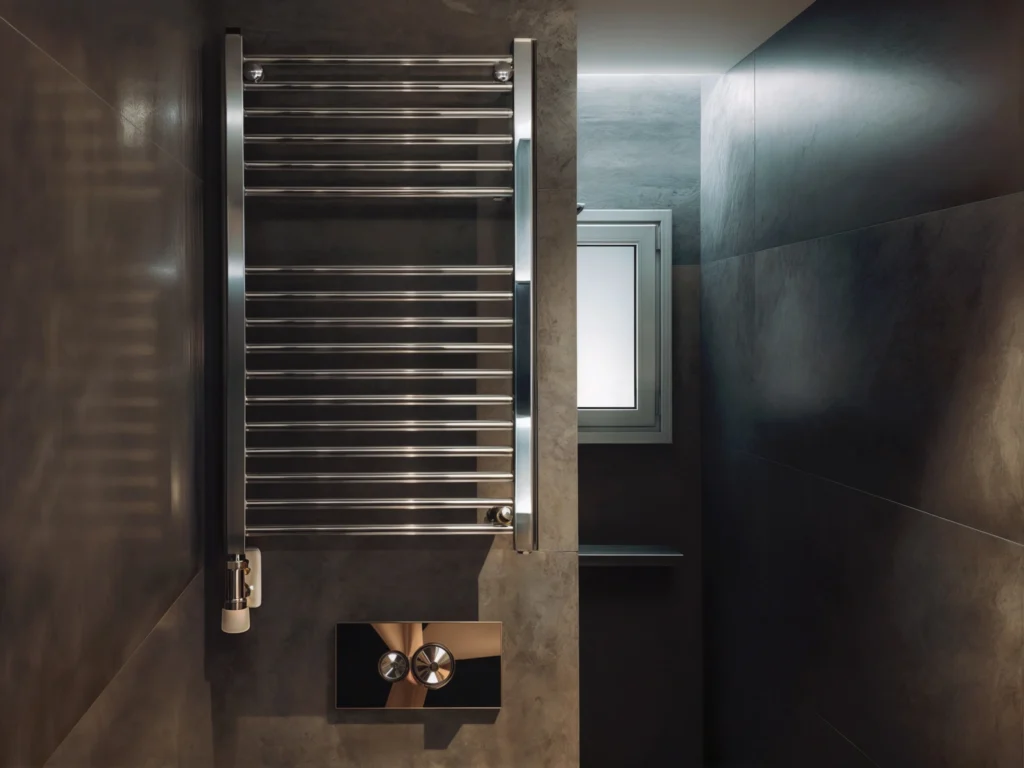 Diseño de interiores moderno en baño elegante en Barcelona Baño moderno con radiador de toallas de acero inoxidable, azulejos oscuros y luz natural en diseño contemporáneo en Barcelona