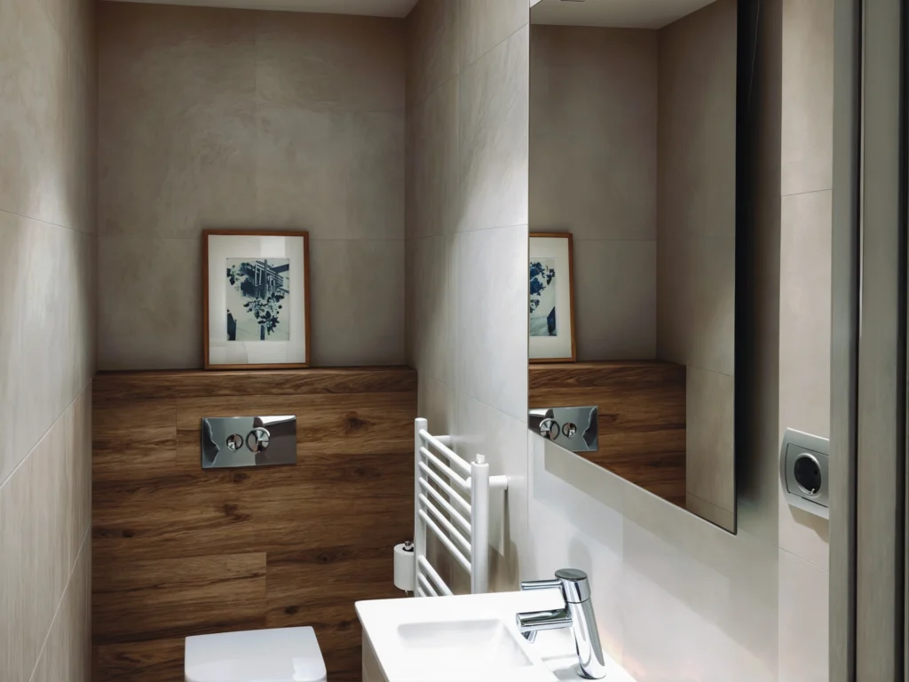 Baño de diseño moderno en Barcelona con acabados de alta gama Moderno baño en Barcelona con muros de cerámica clara, paneles de madera, lavabo contemporáneo y obra de arte minimalista, reflejando tendencias de diseño de interiores y arquitectura de alta gama.