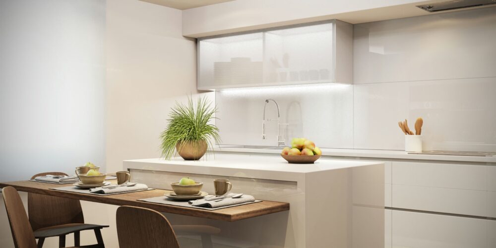 Moderna cocina de diseño interior en Barcelona, destacando una isla central blanca, mesa de madera, utensilios de cocina y frutera con manzanas, iluminada de manera natural.