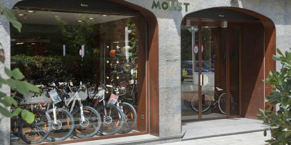 Fachada con arcos de piedra y acero corten en taller Motos Molist, Arbúcies.