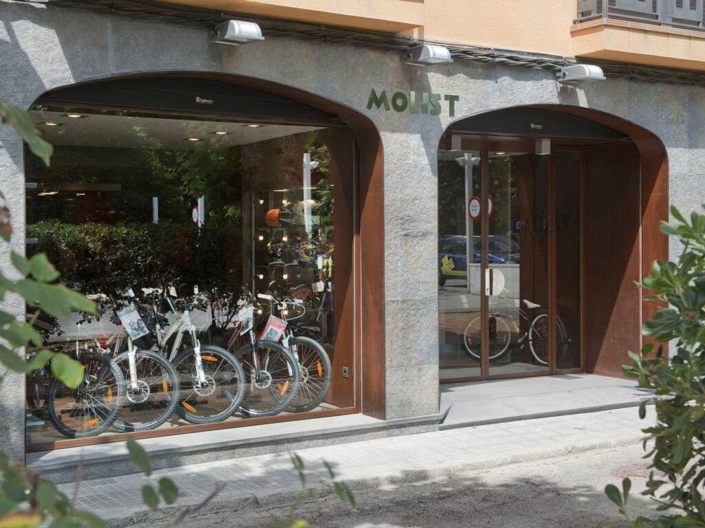 Fachada con arcos de piedra y acero corten en taller Motos Molist, Arbúcies.