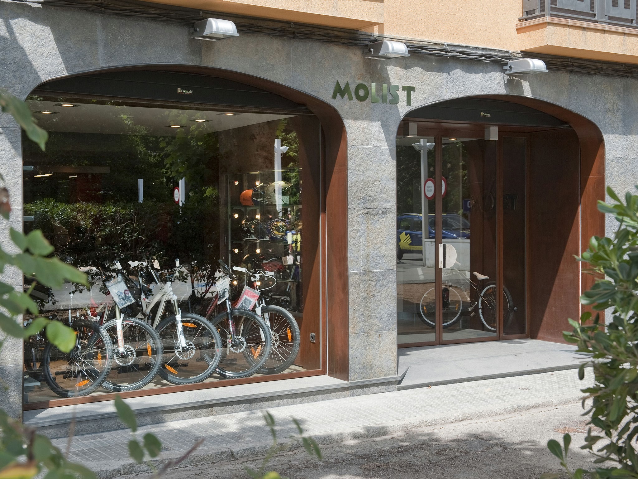Fachada con arcos de piedra y acero corten en taller Motos Molist, Arbúcies.