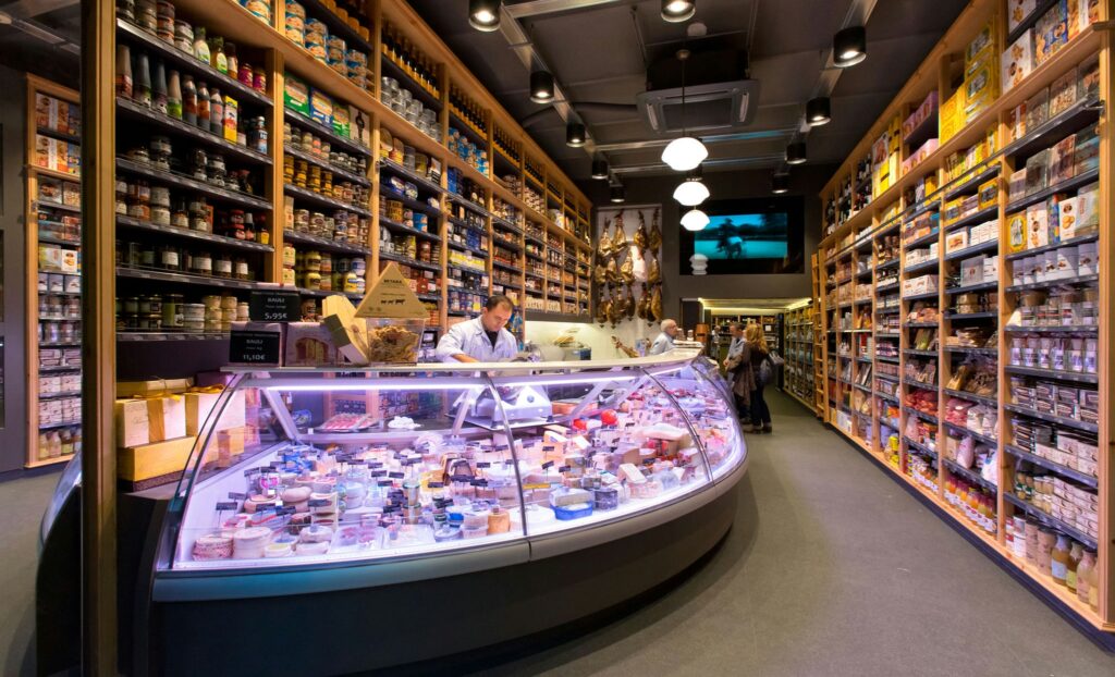 Diseño de Interiores en Tienda Gourmet de Alta Gama en Barcelona Interior de una tienda gourmet de alta gama en Barcelona, destacando un diseño moderno y contemporáneo con materiales de calidad como madera y cristal, y una iluminación natural que realza su estética funcional.