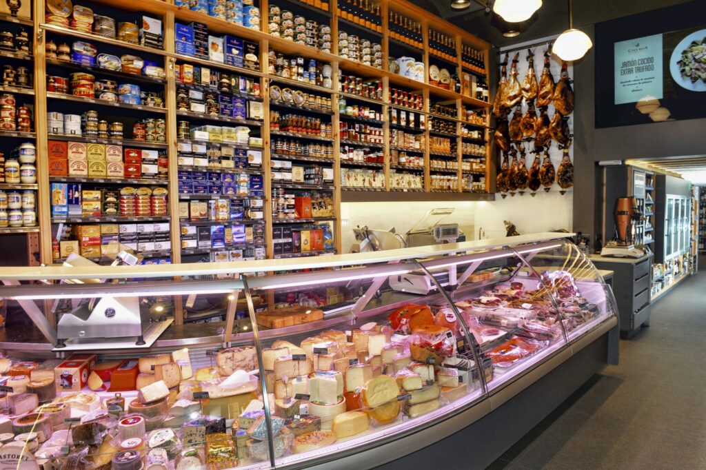 Interior de una tienda gourmet de quesos en Barcelona Interior de un deli de alta gama en Barcelona, mostrando un elegante exhibidor de quesos y productos gourmet, con iluminación natural y diseño moderno.