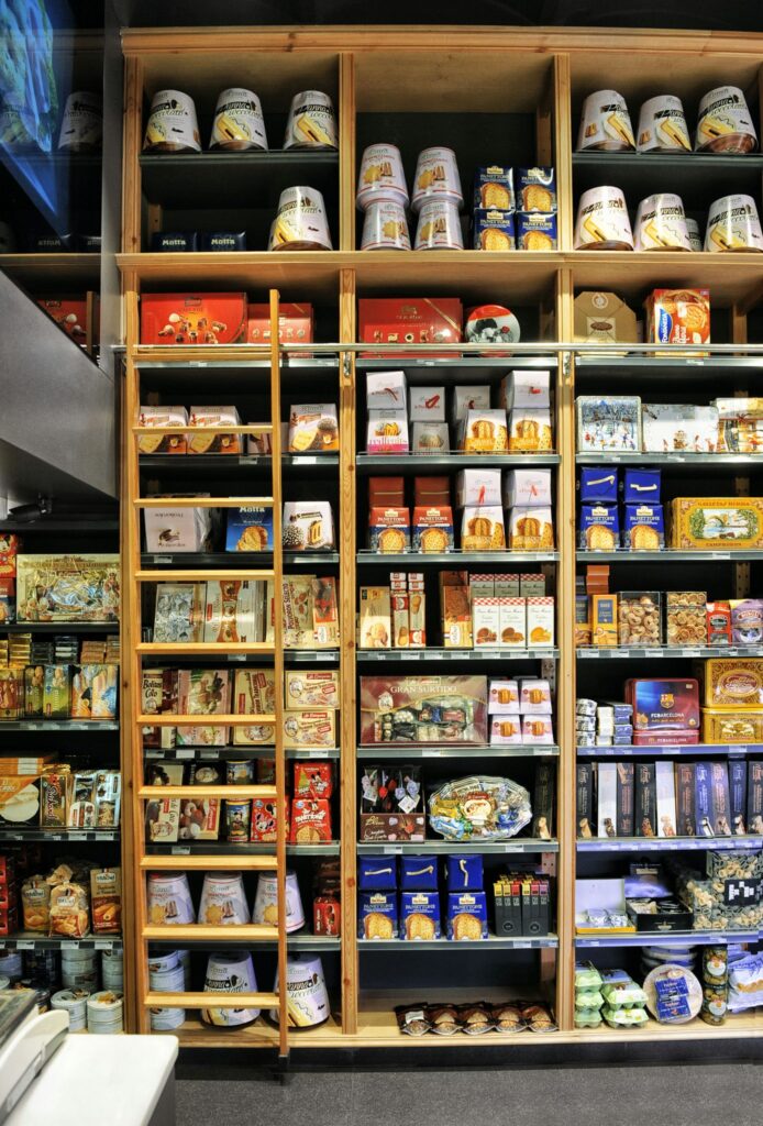 Estantería moderna de alimentos gourmet en tienda de diseño interior de alta gama en Barcelona Estante de madera bien organizado con una variedad de productos alimenticios gourmet, destacando su estética moderna y funcionalidad en un espacio de retail en Barcelona.