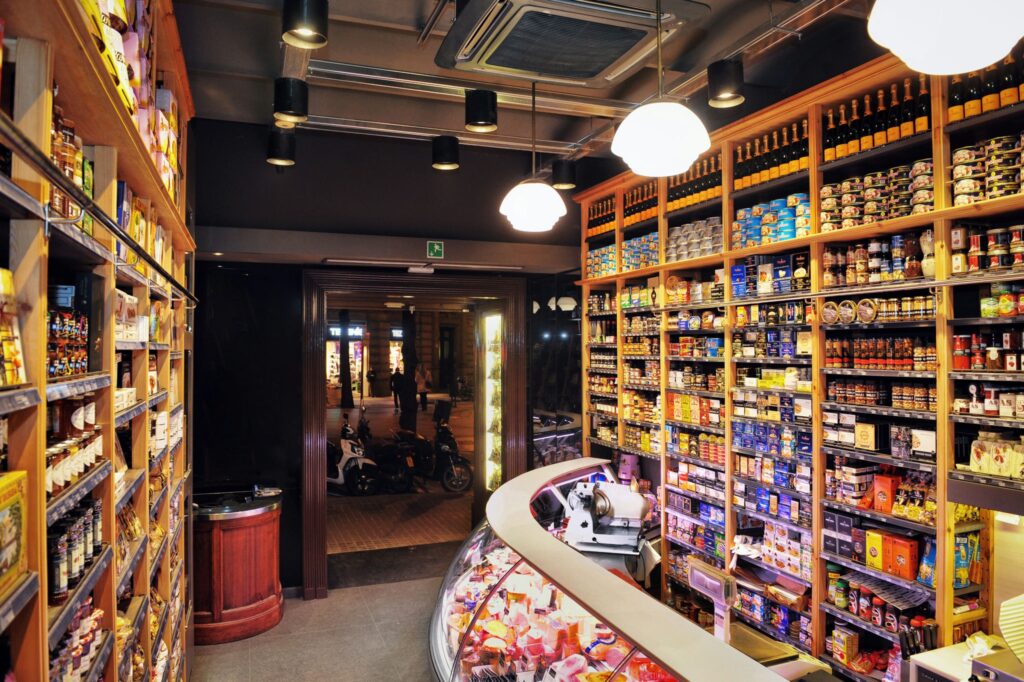 Interior de Tienda Gourmet en Barcelona: Diseño Moderno y Funcionalidad Vista interior de una tienda gourmet en Barcelona, con estanterías de madera y productos variados, mostrando un diseño contemporáneo y funcional.